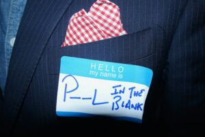 Name tag reading “P—L in the blank” on suit pocket, symbolising you’re not defined by past choices.