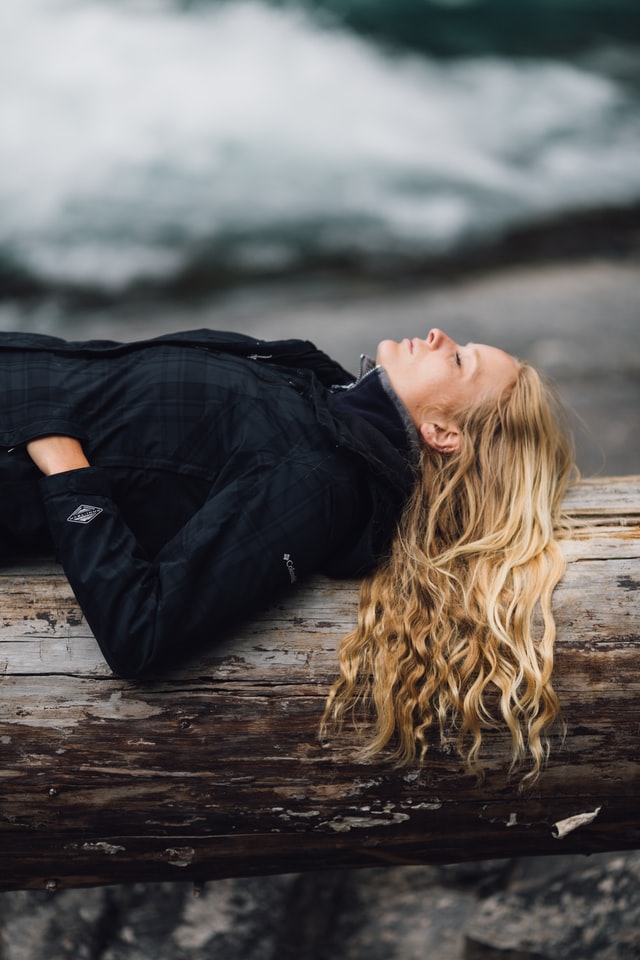 Woman lying on her back outdoors in an article about how to be relaxed by Tess René Coaching