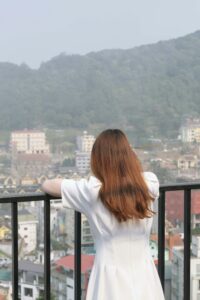 girl looking over fence into foggy distance wearing a white dress