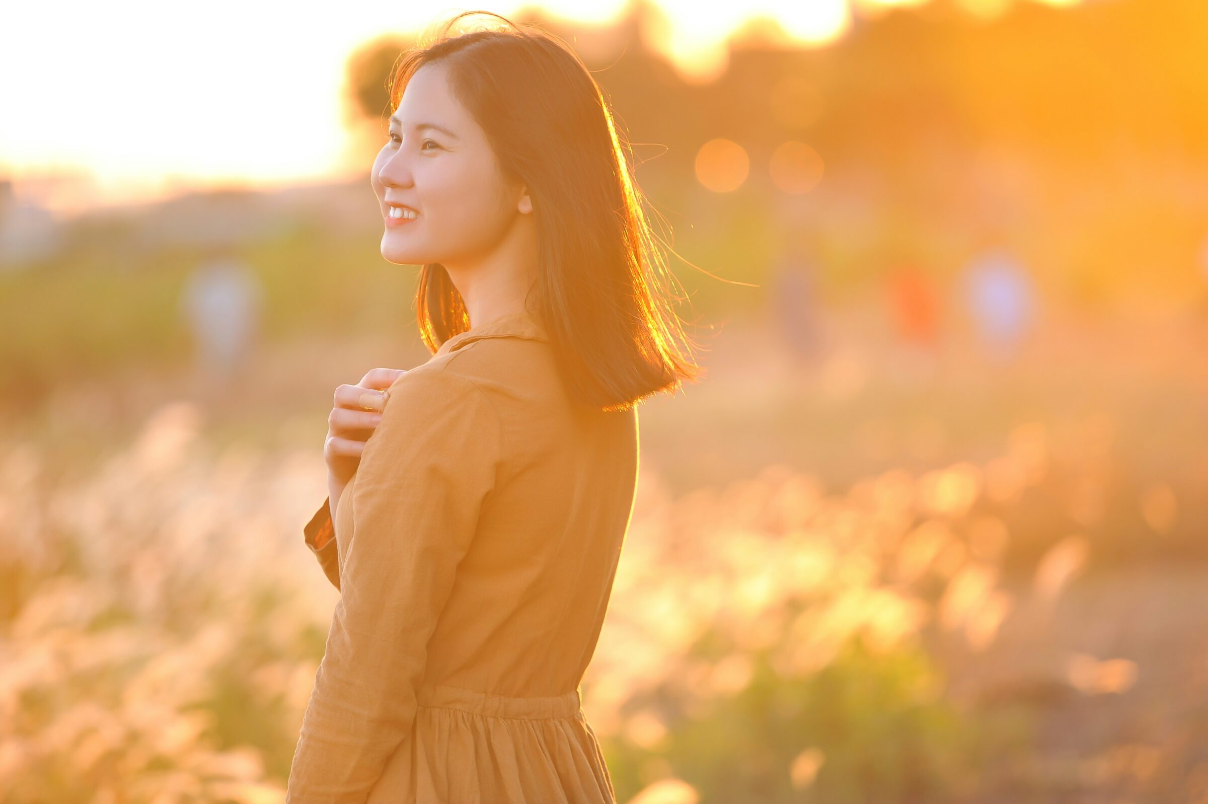 A woman smiling gently at sunrise, symbolizing joy in everyday moments