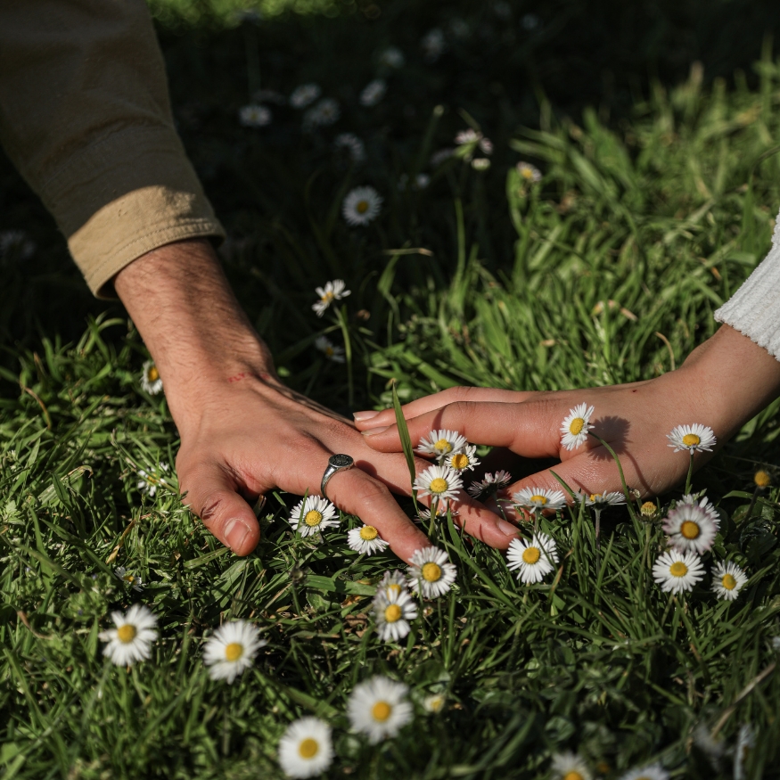 image of two people reaching hands to touch across flowers in a field. Symbolizing healing fear of abandonment. Article from Tess René Coaching on healing the fear of abandonment.