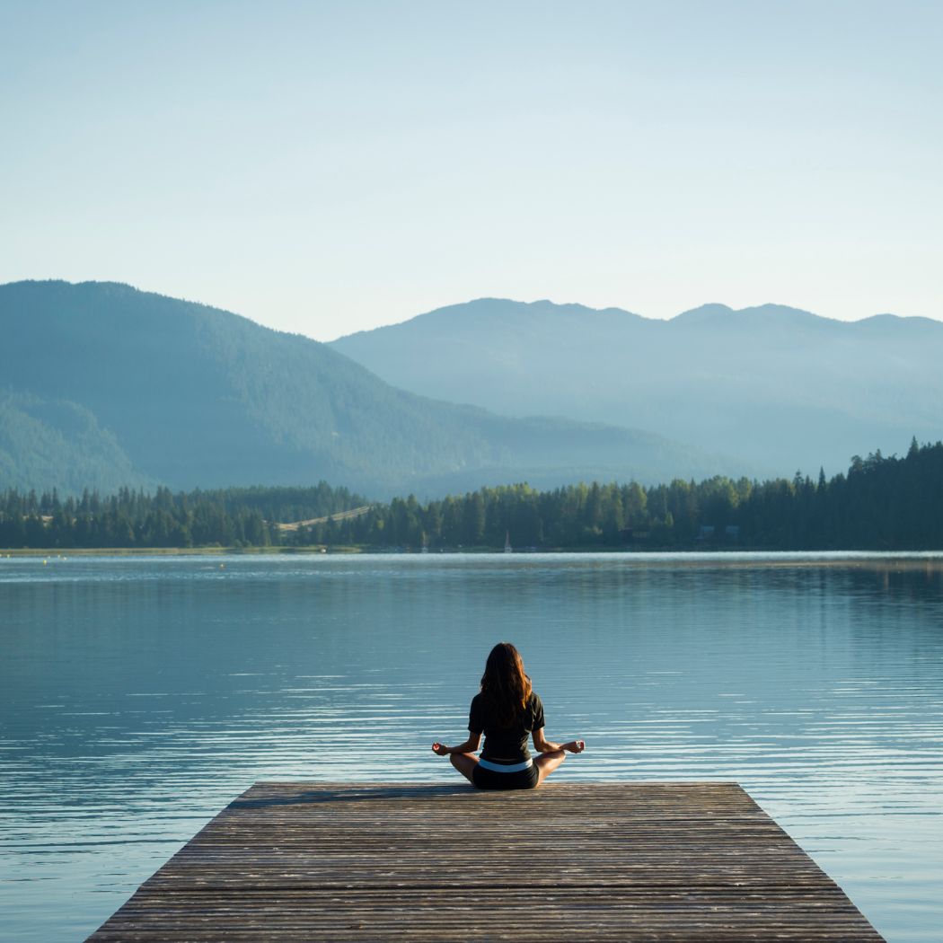 Woman on end of a dock looking into distance in a peaceful seated position. Article from Tess Rene Coaching on self-trust.