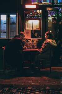 Two people in conversation at night café, symbolising unspoken rules in relationships, in an article by Tess Rene Coaching