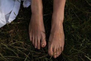 Bare feet standing on grass, grounding through connection to nature — featured in a Tess Rene Coaching piece on calming your inner child with gentle somatic practices