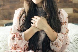 Woman with hands over her heart, wearing a floral blouse, showing self-connection — a practice featured by Tess Rene Coaching