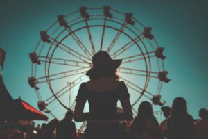 Silhouette of woman in hat with Ferris wheel behind her, evoking awe and perspective — described in Tess Rene Coaching’s joy work