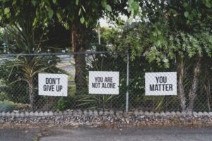 Inspirational signs on a fence, reminding viewers of kindness and value — highlighted in Tess Rene Coaching’s joy reflections