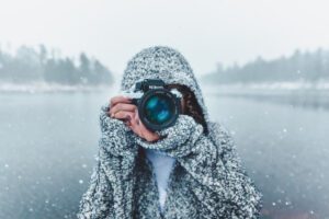 Photographer holding a camera in snow, symbolising how schemas shape perception, in an article by Tess Rene Coaching