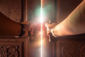 Hands opening wooden doors to bright light, symbolising new possibilities and self-discovery, in article by Tess René Coaching.