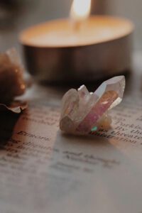 Crystal on an open book with candlelight, representing sensory grounding — highlighted in Tess Rene Coaching’s somatic practice advice