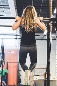 Woman doing chin-ups, symbolising building strength to set personal preferences, in an article by Tess Rene Coaching