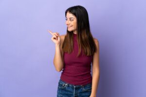 Young woman smiling and pointing with confidence, illustrating growing self trust and reduced indecisiveness in this Tess René Coaching article on building self trust.