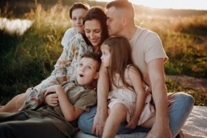 Family sitting together outdoors, shown in an article by Tess René Coaching on early wounds and the question of belonging