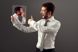 A man pointing at his own reflection, showing confidence and self-encouragement in an article on facing fears by Tess René Coaching.
