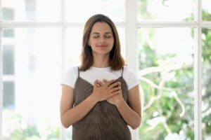 Grounding with hand on chest to ground into emotional regulation in an article by Tess René Coaching