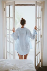 Woman opening doors to fresh air, morning ritual for confidence by Tess René Coaching