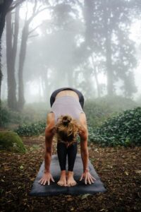 Woman practicing yoga in nature as a grounding morning ritual from Tess René Coaching article