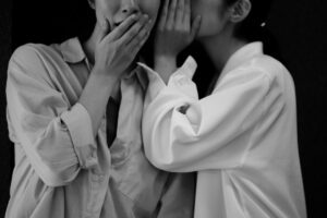 Whispering image symbolising the hidden motives behind perfectionism by Tess René Coaching