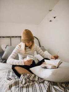 Woman journaling with coffee showing calm action featured in Tess René Coaching’s article on how to be relaxed.