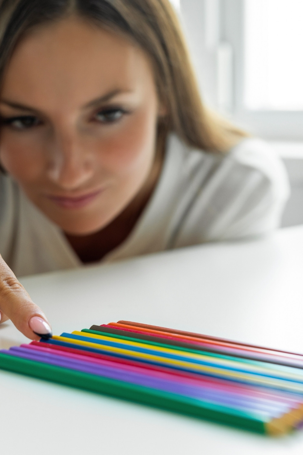 Woman lining up pencils perfectly as featured image in an article about Signs of Perfectionism by Tess René Coaching