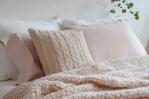 Cozy pillows and blankets on a bed, included in this Tess René Coaching article on comfort and joy.