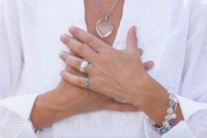 Hands resting over heart symbolising calm acceptance in this Tess René Coaching article about emotions.