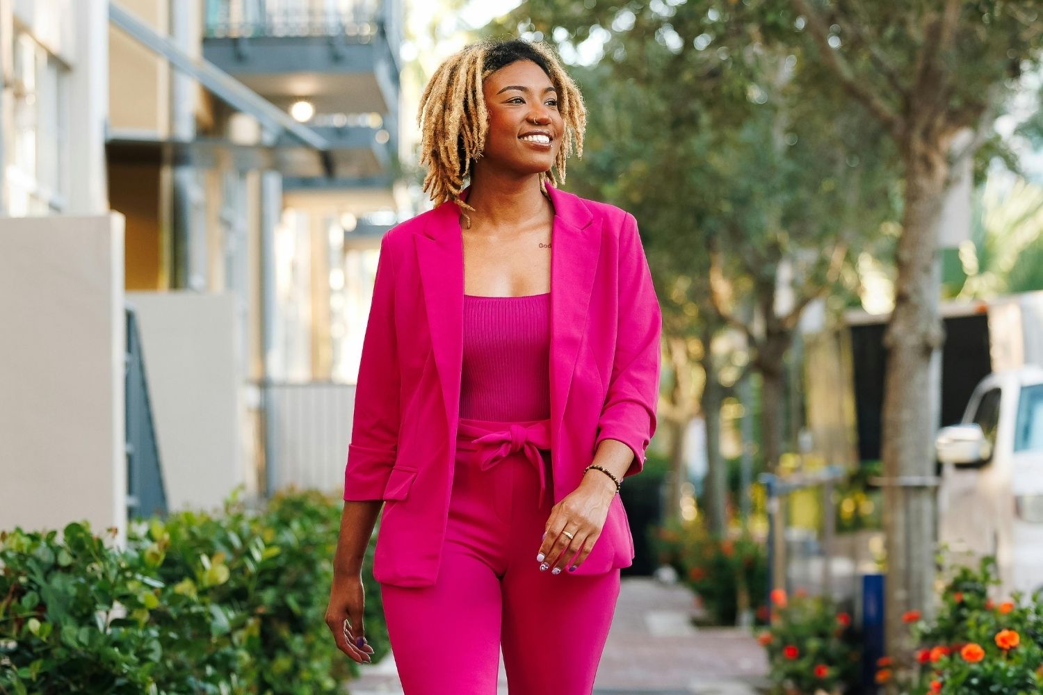 Confident woman walking forward in a bright pink suit, symbolising emotional strength and empowered mindset in this Tess René Coaching article about how to manage emotions