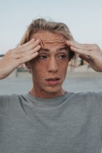 Man holding his head, showing tension and overwhelm in this Tess René Coaching article about how to deal with negative emotions.