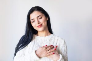 Woman placing hands on heart in this Tess René Coaching article about how to work with our emotions.