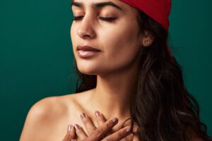 in a Tess René Coaching article on reparenting, a woman places her hands over her heart with calm awareness