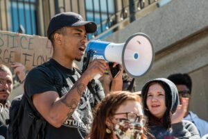 Man using a megaphone during a rally featured in a Tess René Coaching article about finding your voice and speaking up.