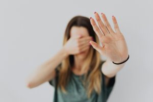 Person covering their eyes with one hand, expressing avoidance and overwhelm, in article by Tess René Coaching about catastrophizing patterns