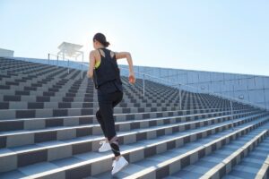 Person running up stairs under bright light, symbolising control and perfectionism, in article by Tess René Coaching on how to stop catastrophizing