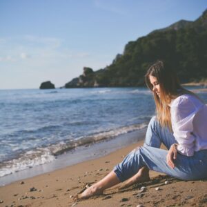 A woman sitting quietly by the ocean in this Tess René Coaching article about how the wound of abandonment affects the nervous system.