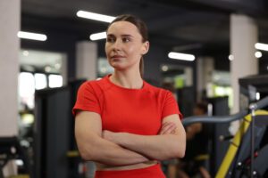 In this Tess René Coaching article, a woman stands strong with arms crossed, representing the courage to allow emotions instead of suppressing them.