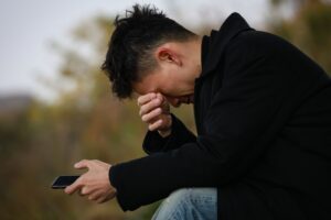 In this Tess René Coaching article about the body’s response to abandonment, a person feels emotional pain and tension while holding a phone representing connection fears.