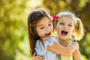 Photo from a Tess René Coaching article showing two children laughing together, symbolising the natural, simple joy of connection.