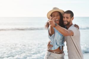 Couple laughing together by the ocean in an article by Tess René Coaching about simple connection.