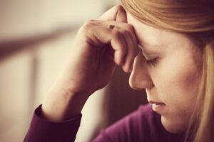 A woman resting her forehead on her hand, reflecting quietly in an article about handling disappointment in life by Tess René Coaching