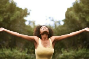 From a Tess René Coaching article about grounding to stop the alarm response, a woman raises her hands to the sky in grounding presence.