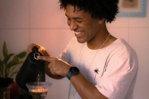 Man smiling while making coffee in an article by Tess René Coaching about micro moments of joy.