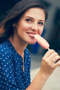 Smiling woman enjoying a popsicle used in a Tess René Coaching article about joy as a steady state and the gentle side of nervous system change.