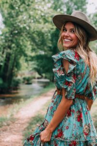 A joyful woman walking near a river, featured in a Tess René Coaching article about creating joy in hard times slowly and gently.