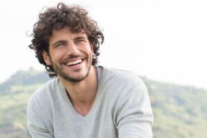 Man smiling warmly outdoors in an article by Tess René Coaching about reconnecting with pleasure.