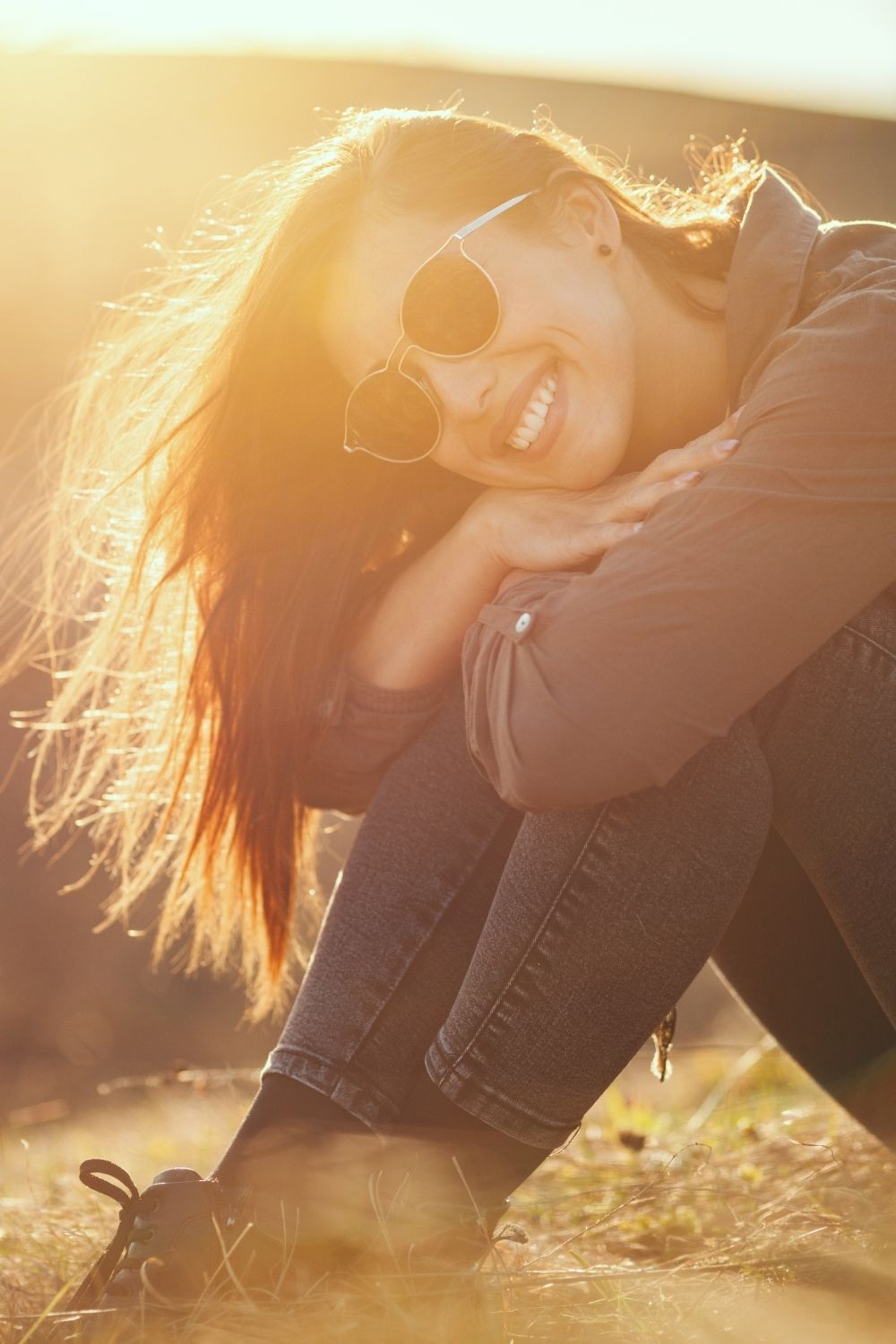 Smiling woman in sunlight symbolising warmth and safety in an article about healing the nervous system by Tess René Coaching