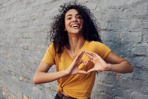 Woman making a heart shape with her hands in a Tess René Coaching article about letting transformation be something you feel in your body.