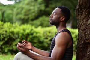 Man sitting in meditation under a tree, practising embodied healing for loss and grief in an article by Tess René Coaching