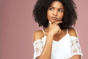 Woman in thoughtful pose representing a moment of noticing unhelpful thinking patterns, in an article by Tess Rene Coaching about releasing perfectionistic standards.