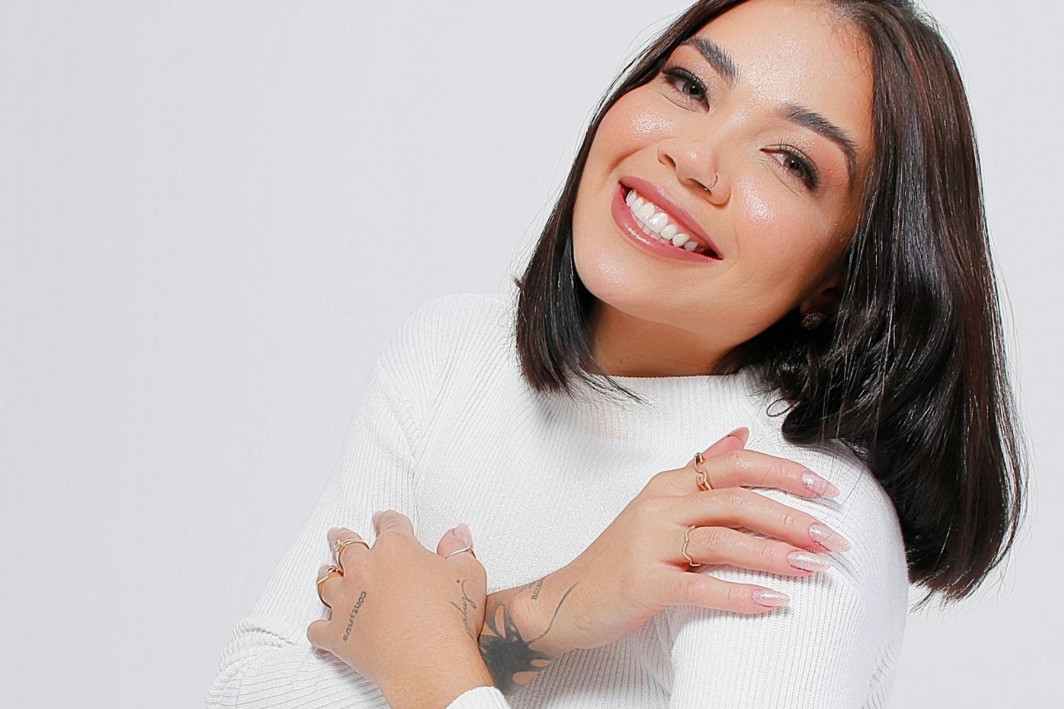 Woman smiling and holding herself in a warm embrace featured in a Tess Rene Coaching article about opening my heart