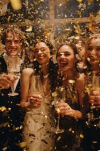 Group of friends laughing under falling confetti shown in this Tess René Coaching article on playful nervous system healing and feeling safe with others